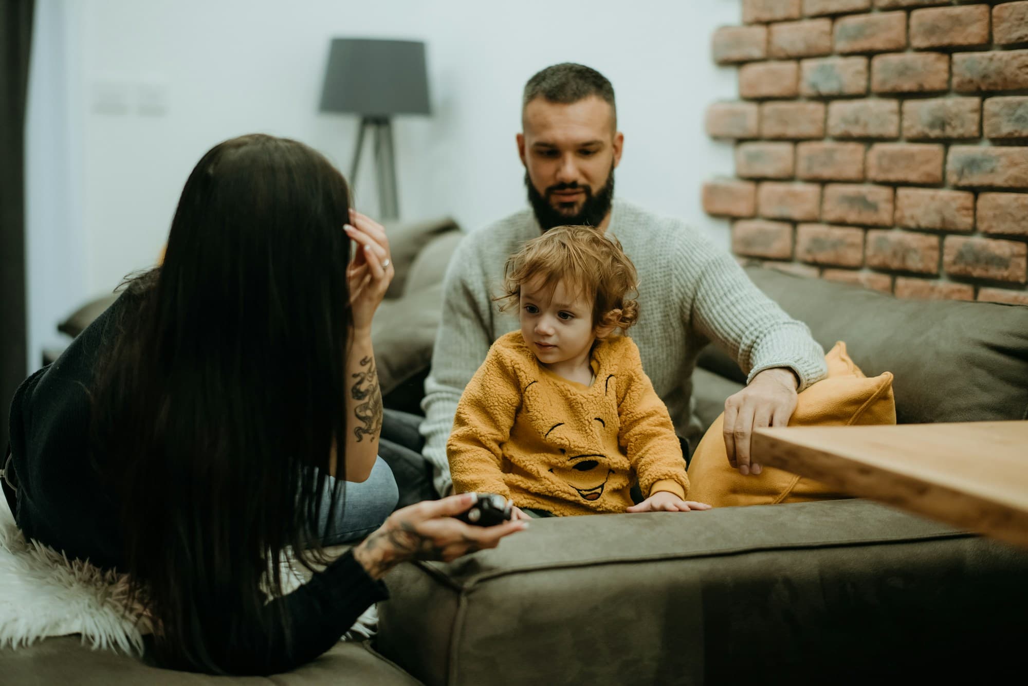 Mom, dad, and their toddler relaxing together on the living room couch at home